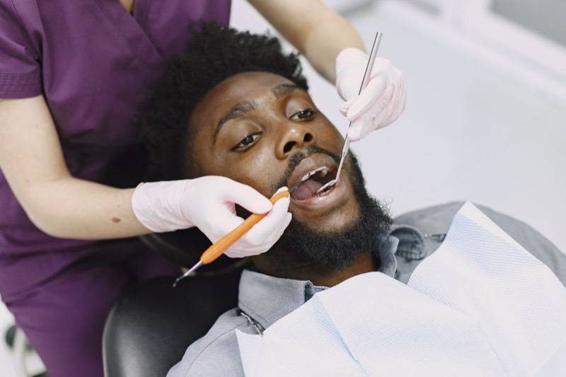 Odontólogo realizando un tratamiento a un paciente en el sillón dental